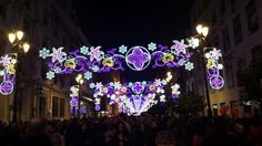 people are walking under an archway decorated with lights