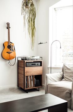 a living room with a guitar hanging on the wall next to a record player stand