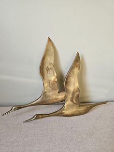 two brass bird sculptures sitting on top of a table