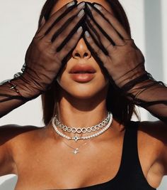 a woman with her hands covering her eyes and wearing a choker, black sheer sleeved top