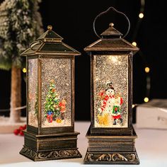 two lighted christmas lanterns sitting next to each other on top of a white tablecloth covered table