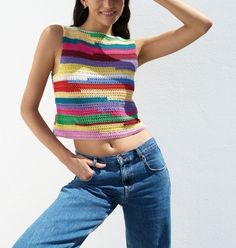 a woman posing in jeans and a colorful top