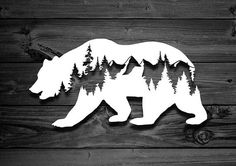 a bear with trees cut out of it's back on a wooden background,