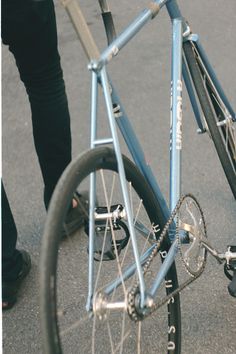 a blue bicycle is parked on the side of the road with someone standing next to it