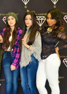 three young women standing next to each other in front of a diamond wall with the words fifth harmony written on it