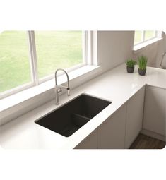 a kitchen with white counter tops and black sink in front of a window that looks out onto the grass