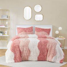 a bed with pink and white bedspread in a small room next to two round mirrors on the wall