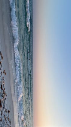 an aerial view of the beach with surfers in the water and snow on the ground