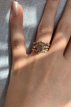 a woman's hand with two gold rings on it and a diamond ring in the middle