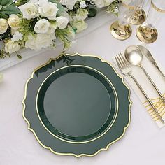 a table setting with white flowers and gold cutlery, plates and utensils