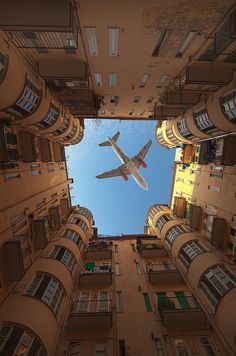 an airplane is flying high in the sky between two buildings, looking up at it