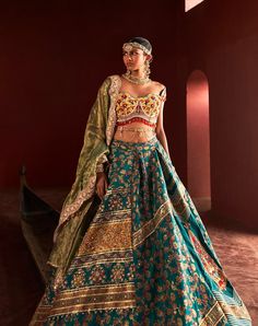 Embrace your look with this chic teal green kani silk lehenga set, an exquisite embodiment of timeless elegance. Featuring a beautifully cutwork neckline and cap sleeve blouse, it is adorned with heavy hand embroidery that adds a soft touch while blending modern and traditional aesthetics. The blouse is further enhanced with colorful bead appliqué along the borders for a luxurious finish. Completing the ensemble is a shimmering dupatta and a meticulously crafted handmade belt that defines the waistline, beautifully merging sophistication with artisanal craftsmanship. Cap Sleeves Blouse, Handmade Belts, Indian Heritage, Silk Lehenga, Beaded Applique, Cut Work, Teal Green, Fantasy Clothing, Silk Blouse