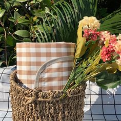 some flowers are sitting in a basket on a table next to a potted plant