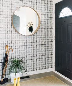 a black and white checkered wall with a round mirror on the wall next to a potted plant