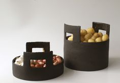 two black containers filled with potatoes on top of a white table