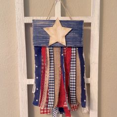 an american flag decoration hanging on a door with a wooden star and ribbon around it