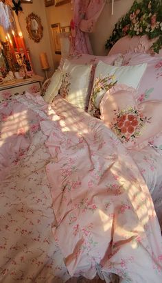 an unmade bed with pink and white comforter, pillows and flowers on it