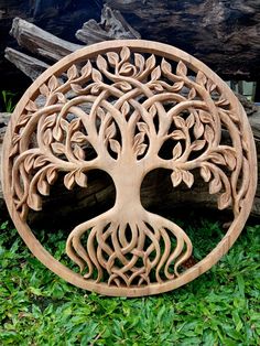 a wooden carving of a tree with its roots in the shape of a circle on some grass