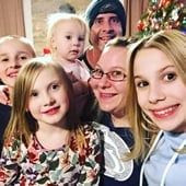 a group of people standing next to each other in front of a christmas tree with presents on it