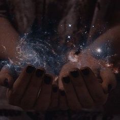 two hands holding something in front of them with stars all over the space behind them