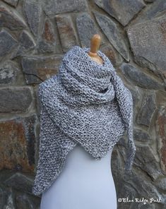 a white mannequin wearing a gray knitted shawl