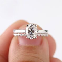 a close up of a person's hand holding an engagement ring