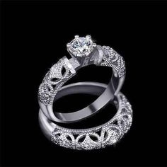 two wedding rings with an intricate design on the band and center diamond in the middle