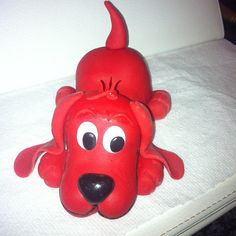 a red dog head sitting on top of a white bed with black eyes and nose