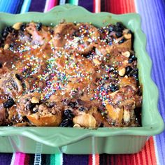 a green casserole dish filled with fruit and sprinkles on a colorful table cloth