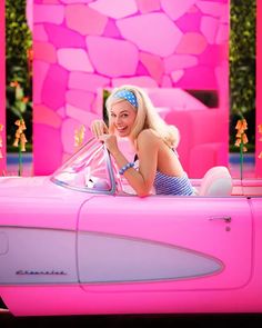 a woman is sitting in a pink car