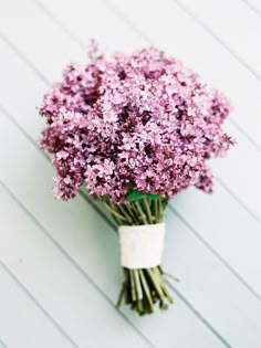 a bunch of purple flowers sitting on top of a white table next to a wall