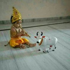 a baby sitting on the floor next to a toy cow with horns and headdress