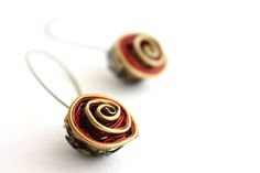 two small red and gold earrings on white surface with wire wrapped around the ear wires