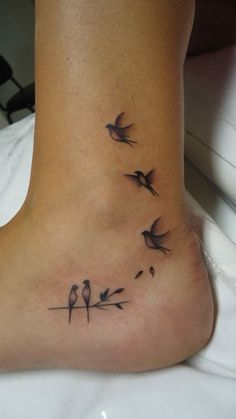 a small foot tattoo with birds on it