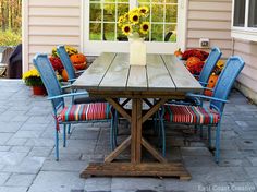 a wooden table with blue chairs around it and sunflowers in the window sill