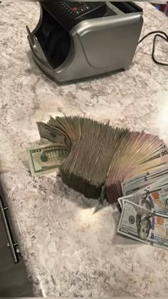 a pile of money sitting on top of a counter next to a silver toaster