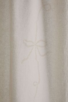 a close up view of a white curtain with an intricate design on the bottom half