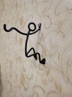 a black hook on the side of a wall with an artistic design behind it,