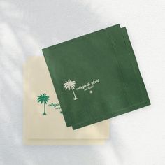 two green napkins with palm trees on them