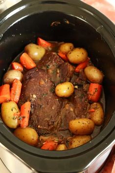 pot roast with carrots and potatoes in the crock pot on top of a table