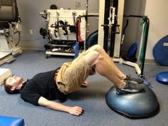 a man is doing exercises on an exercise ball in the gym while lying on his back