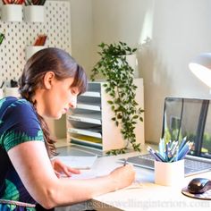 a woman sitting at a desk with a laptop and papers in front of her,