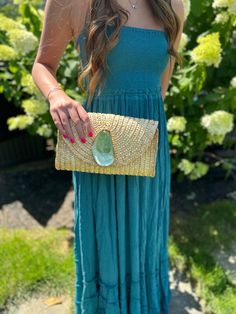 a woman in a blue dress holding a straw bag