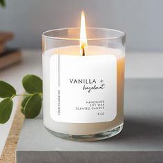 a white candle sitting on top of a table next to a green leafy plant