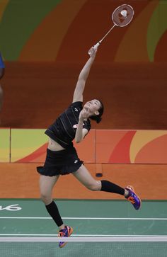 a female tennis player is jumping to hit the ball with her racket in mid air