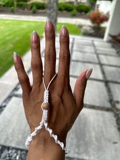 a woman's hand wearing a white bracelet with a pearl bead on it