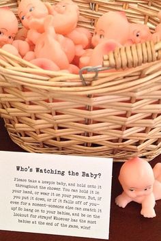 a basket filled with small plastic pigs next to a sign that says who's watching the baby?