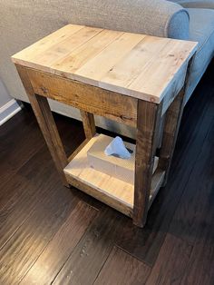 a wooden table sitting on top of a hard wood floor next to a gray couch