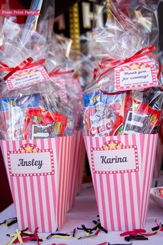 two pink striped boxes with candy and candies in them sitting on a white table