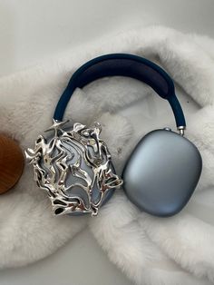 a pair of headphones sitting on top of a white fur covered blanket next to a wooden object